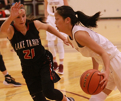Below, Tiger guard Madi North speeds by Lake Travis Cavalier guard Natalie Paxton during a tournament game played at Tiger Gym. Dripping Springs opened 26-5A play with a loss to Seguin at home last week. (photo by Moses Leos III)