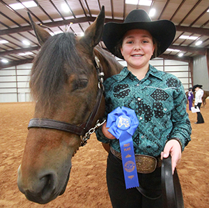 Kylie Baker, a 7th grader from Dripping Springs, proudly holds her blue ribbon earned in the junior showmanship competition at the Hays County Livestock Show and Expo horse show Saturday at Dripping Springs Ranch Park in Dripping Springs. (photo by Moses Leos III)